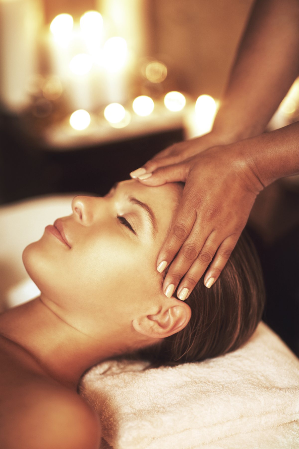 Therapist applying gentle acupressure at the temples during a candlelit Chinese head massage